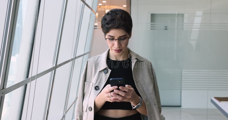 Femme d'affaires arménienne attrayante utilisant un smartphone au bureau banque de vidéos