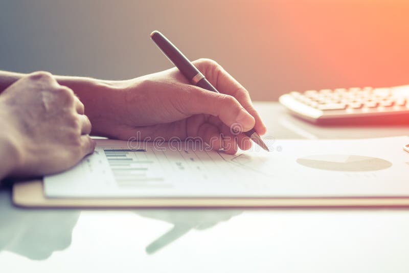Femme d'affaires de l'Asie analysant des diagrammes d'investissement sur le bureau photographie stock Femme d'affaires de l'Asie analysant des diagrammes d'investissement sur le bureau photographie stock