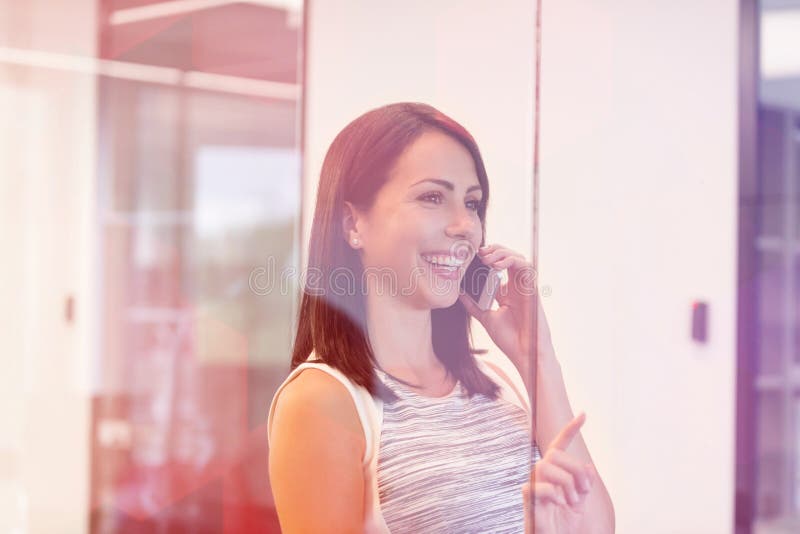 Femme d'affaires de sourire parlant au t?l?phone portable au bureau image libre de droits Femme d'affaires de sourire parlant au t?l?phone portable au bureau image libre de droits