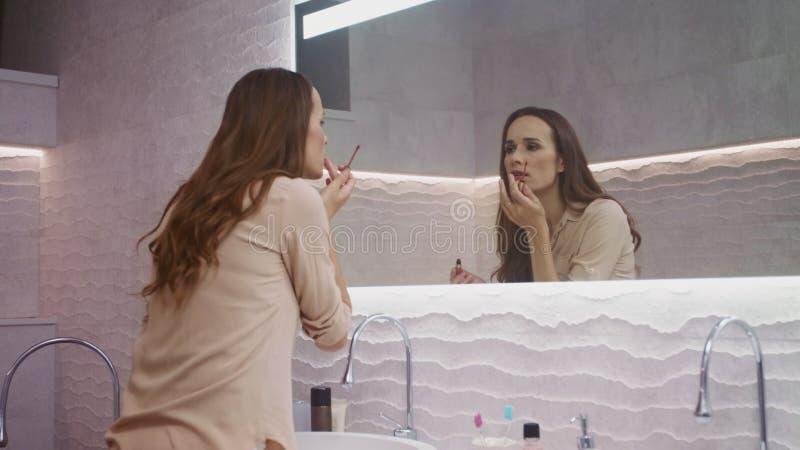 Femme d'affaires faisant le maquillage dans la salle de bains Personne féminine de beauté regardant le miroir