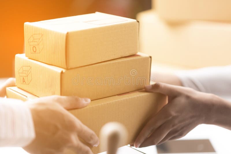 Femme d'affaires heureuse recevant un paquet se reposant sur un bureau à image libre de droits Femme d'affaires heureuse recevant un paquet se reposant sur un bureau à image libre de droits