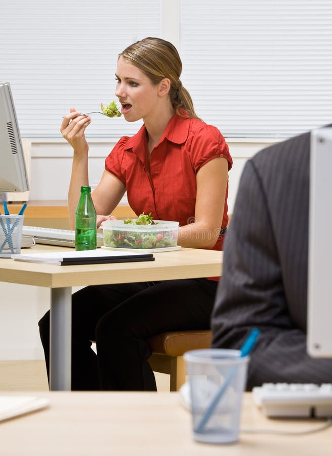 Femme d'affaires mangeant de la salade au bureau photo stock