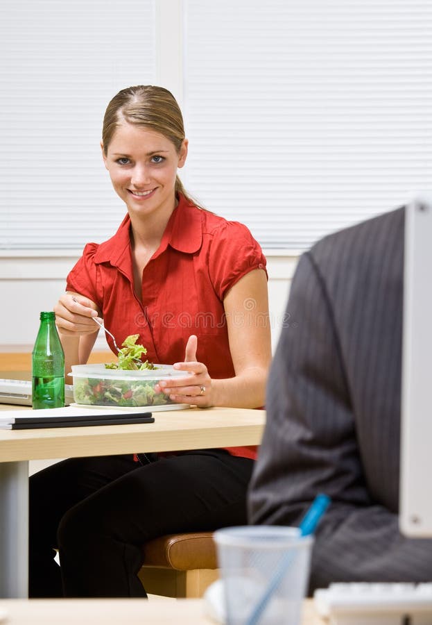 Femme d'affaires mangeant de la salade au bureau photographie stock libre de droits