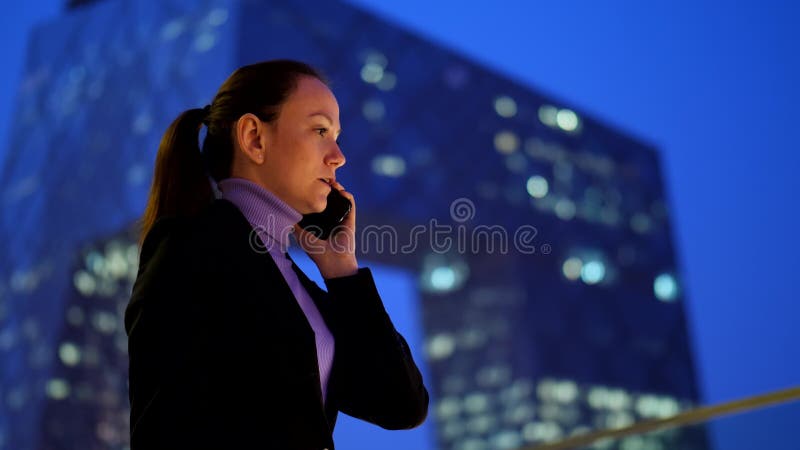 Femme d'affaires parlant sur le téléphone portable contre le gratte-ciel au centre ville