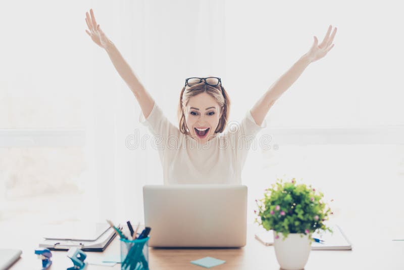 Femme d'affaires réussie enthousiaste heureuse triomphant avec l'ordinateur portable se reposant sur le lieu de travail de poste photographie stock libre de droits