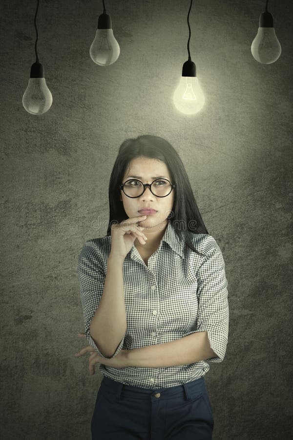 Femme d'affaires songeuse sous une ampoule lumineuse photo libre de droits Femme d'affaires songeuse sous une ampoule lumineuse photo libre de droits