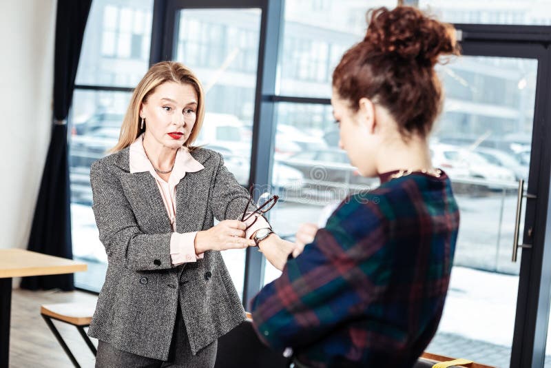 Femme d'affaires stricte parlant à son secrétaire inexpérimenté photographie stock Femme d'affaires stricte parlant à son secrétaire inexpérimenté photographie stock