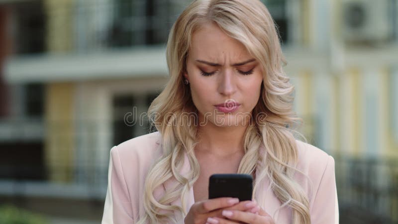 Femme d'affaires sérieuse de portrait à l'aide de l'extérieur smartphone. Femme au téléphone en tapant clips vidéos