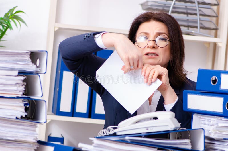 Femme d'affaires d'une cinquantaine d'années peu satisfaite du travail excessif photo libre de droits Femme d'affaires d'une cinquantaine d'années peu satisfaite du travail excessif photo libre de droits