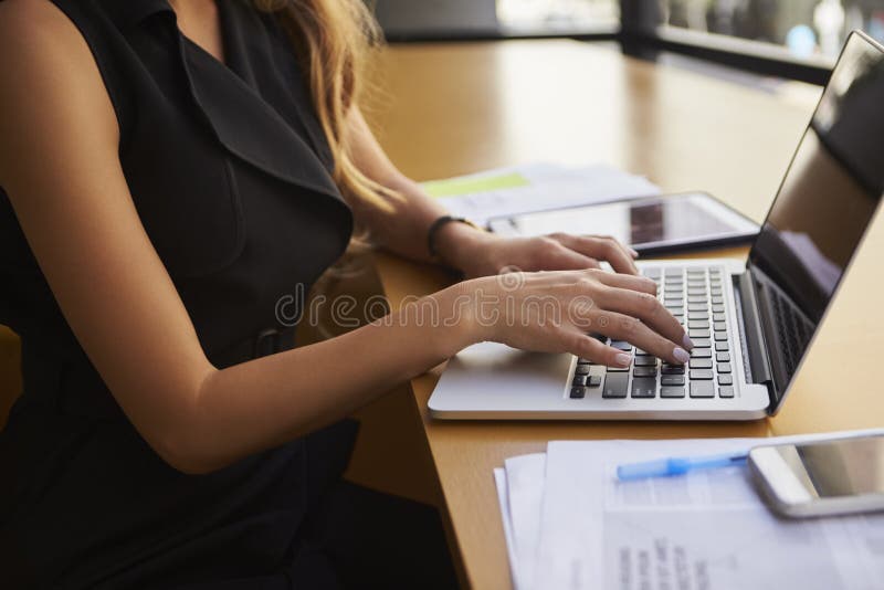 Femme d'affaires à l'aide de l'ordinateur portable dans le bureau, mi section, vue de côté photos stock Femme d'affaires à l'aide de l'ordinateur portable dans le bureau, mi section, vue de côté photos stock