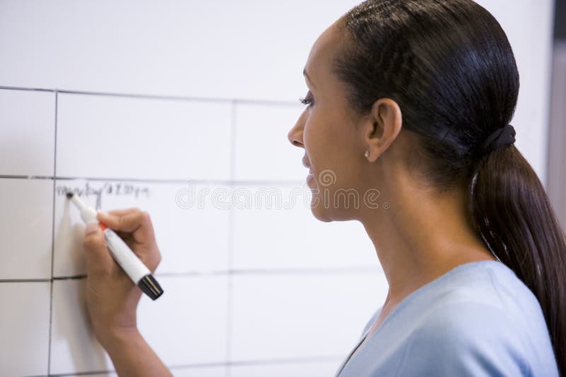 Femme d'affaires écrivant à l'intérieur sur le panneau effaçable photo stock Femme d'affaires écrivant à l'intérieur sur le panneau effaçable photo stock