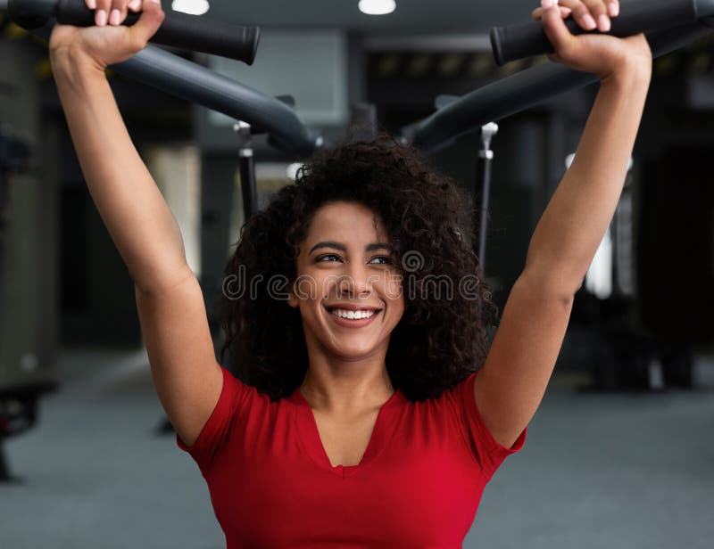 Femme d'afro-américain s'exerçant au gymnase sur la machine photo stock Femme d'afro-américain s'exerçant au gymnase sur la machine photo stock