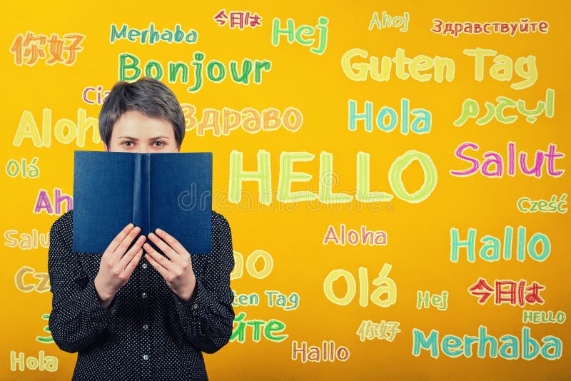Femme d'étudiant tenant un manuel au-dessus du mur jaune écrit avec le mot bonjour traduit en différentes langues Occasion pour images libres de droits Femme d'étudiant tenant un manuel au-dessus du mur jaune écrit avec le mot bonjour traduit en différentes langues Occasion pour images libres de droits