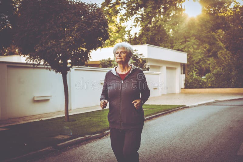 Femme dans l'habillement de sports pulsant en parc de ville photo stock Femme dans l'habillement de sports pulsant en parc de ville photo stock