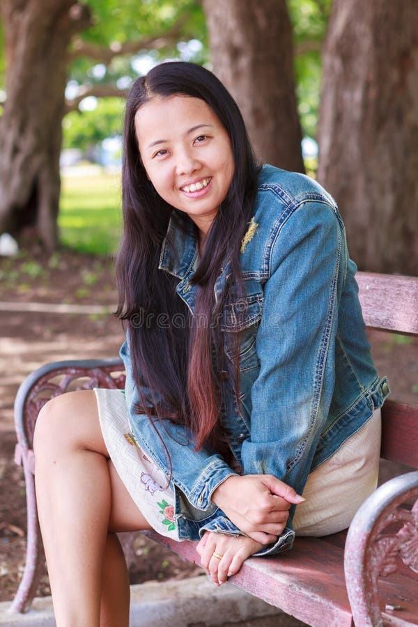Femme dans la chemise de jeans souriant en parc photographie stock Femme dans la chemise de jeans souriant en parc photographie stock