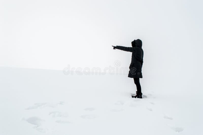 Femme dans la neige dirigeant son doigt vers l'espace vide images libres de droits Femme dans la neige dirigeant son doigt vers l'espace vide images libres de droits