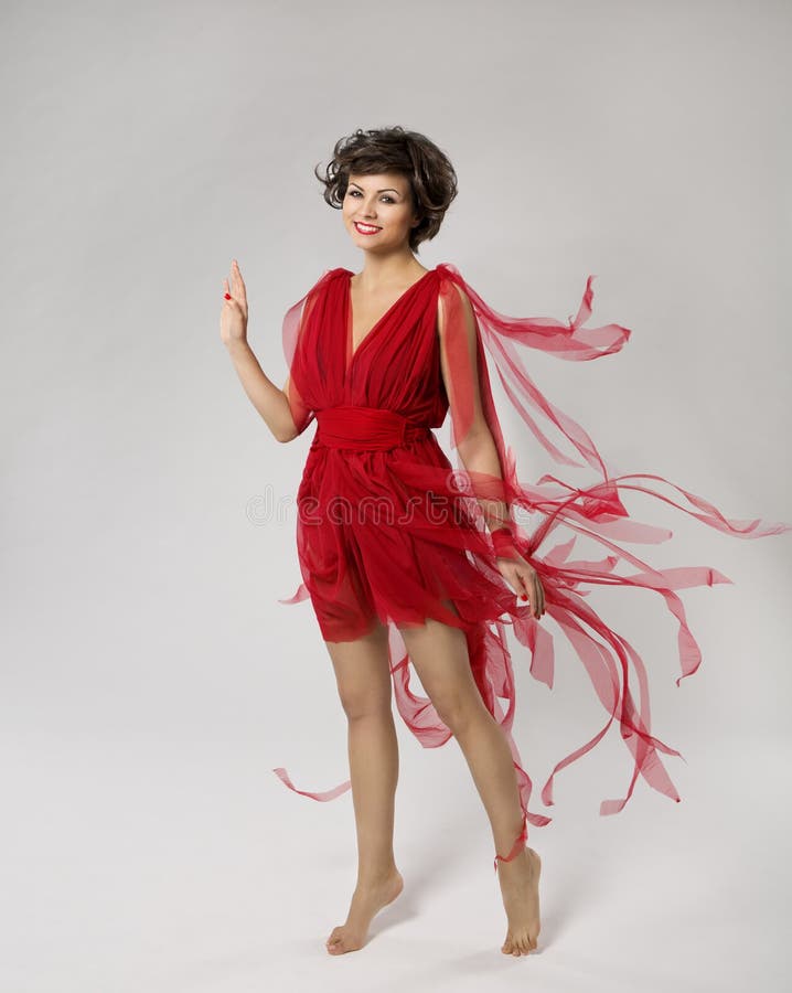 Femme dans la robe rouge de beauté, main de ondulation de belle fille, vêtements volant et flottant sur le vent, jeune mannequin image stock Femme dans la robe rouge de beauté, main de ondulation de belle fille, vêtements volant et flottant sur le vent, jeune mannequin image stock