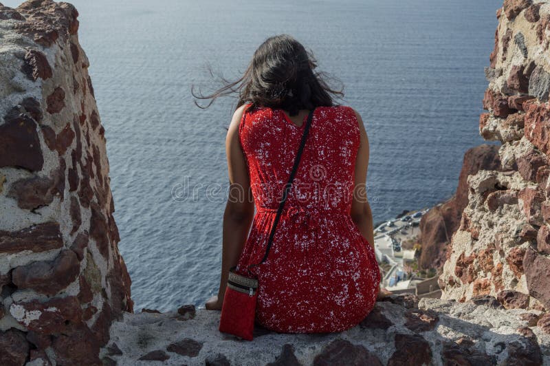 Femme dans la robe rouge regardant la mer à Oia, Santorini, Cyclade photos libres de droits Femme dans la robe rouge regardant la mer à Oia, Santorini, Cyclade photos libres de droits