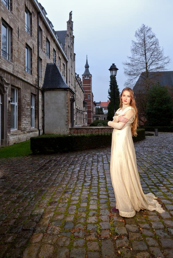 Femme dans la robe victorienne dans une vieille place de ville le soir dans le profil images stock Femme dans la robe victorienne dans une vieille place de ville le soir dans le profil images stock