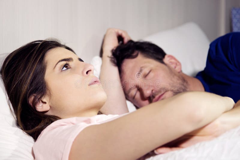 Femme dans le lit avec l'ami pensant aux relations tandis que l'homme dort photos libres de droits Femme dans le lit avec l'ami pensant aux relations tandis que l'homme dort photos libres de droits