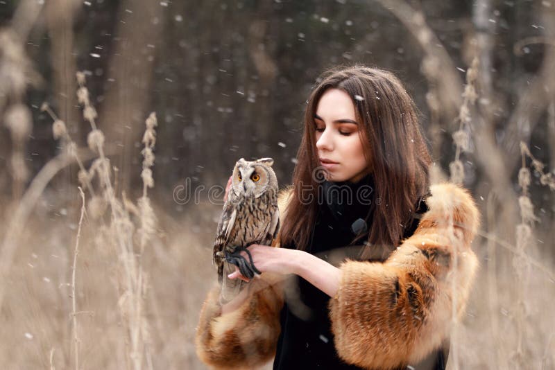 Femme dans le manteau de fourrure avec le hibou en main par la première neige d'automne Beautif image stock Femme dans le manteau de fourrure avec le hibou en main par la première neige d'automne Beautif image stock