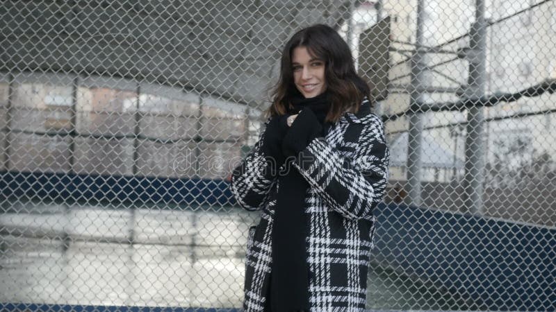 Femme dans le manteau près de la barrière nette banque de vidéos