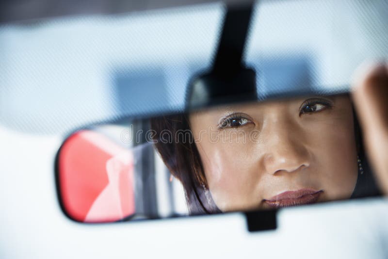 Femme dans le miroir de rearview image libre de droits Femme dans le miroir de rearview image libre de droits