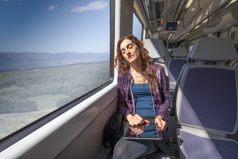 Femme dans le train dormant avec le comprimé numérique dans des mains photographie stock