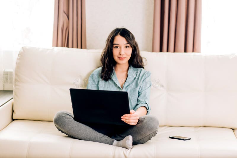 Femme de Bbeautiful ? l'aide de l'ordinateur portable ? la maison sur le sofa images libres de droits Femme de Bbeautiful ? l'aide de l'ordinateur portable ? la maison sur le sofa images libres de droits