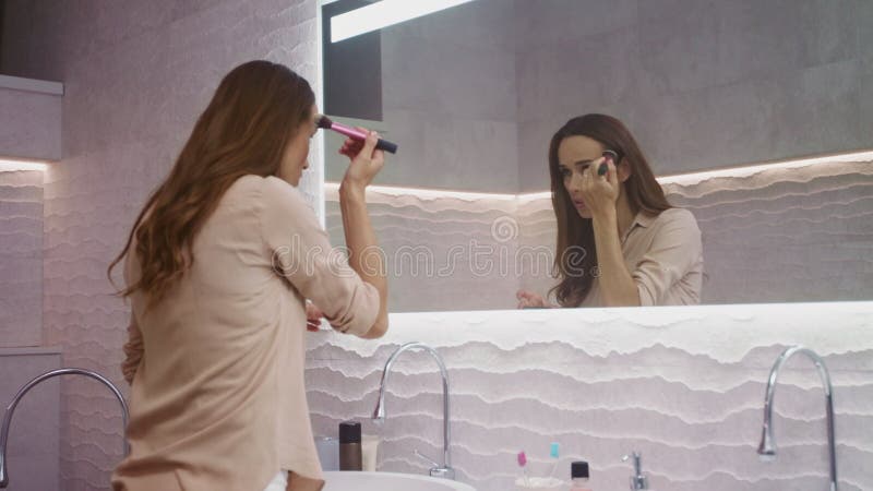 Femme de beauté faisant le maquillage dans la salle de bains Femme heureuse faisant le maquillage de matin