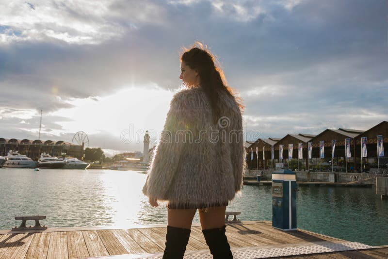 Femme de brune avec le portrait de manteau de fourrure se tenant dehors, avec le soleil ? l'arri?re-plan photo libre de droits Femme de brune avec le portrait de manteau de fourrure se tenant dehors, avec le soleil ? l'arri?re-plan photo libre de droits