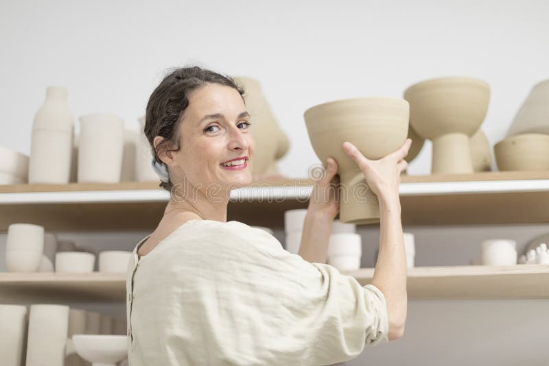 Femme de Ceramist tenant un potier dans son studio image stock Femme de Ceramist tenant un potier dans son studio image stock