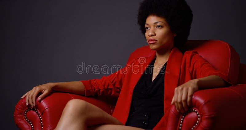 Femme De Couleur Attirante Forte S'asseyant Dans La Chaise Rouge Image