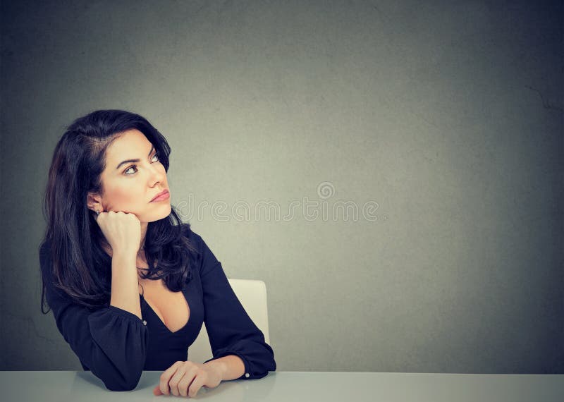 Femme de pensée d'affaires s'asseyant au bureau photo stock Femme de pensée d'affaires s'asseyant au bureau photo stock