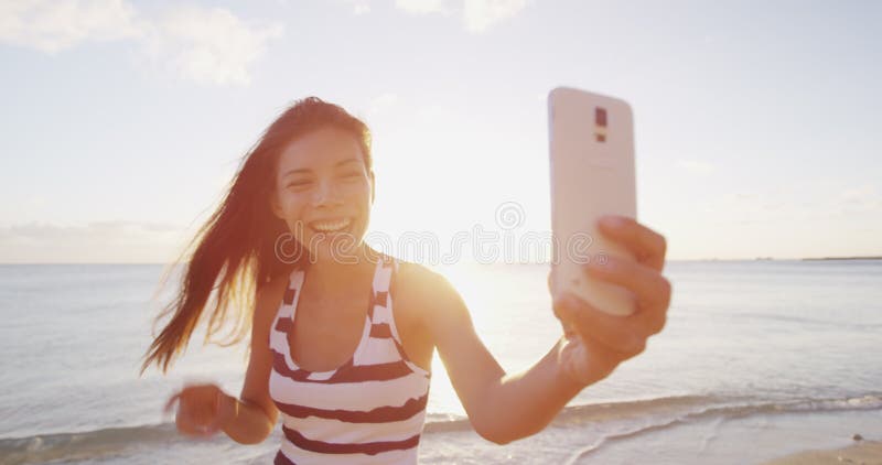 Femme de selfie en prenant des photos au téléphone avec le sourire smartphone heureux sur la plage