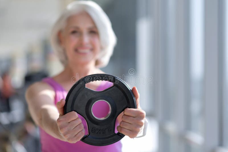 Femme de sourire assez supérieure tenant l'équipement de sport photo libre de droits Femme de sourire assez supérieure tenant l'équipement de sport photo libre de droits