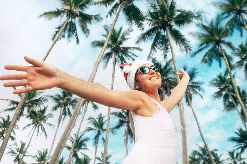 Femme de sourire heureuse dans le séjour de chapeau de Santa sous des palmiers Christma photographie stock