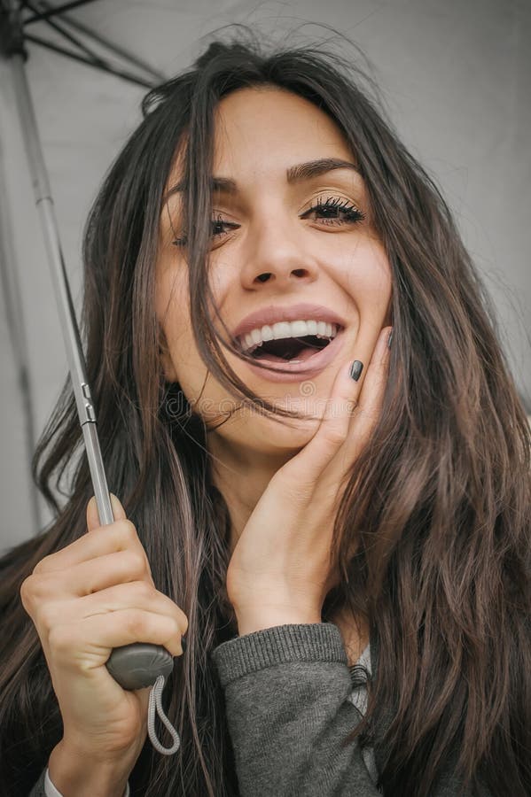 Femme de sourire heureuse sous le parapluie sous la pluie photos stock Femme de sourire heureuse sous le parapluie sous la pluie photos stock
