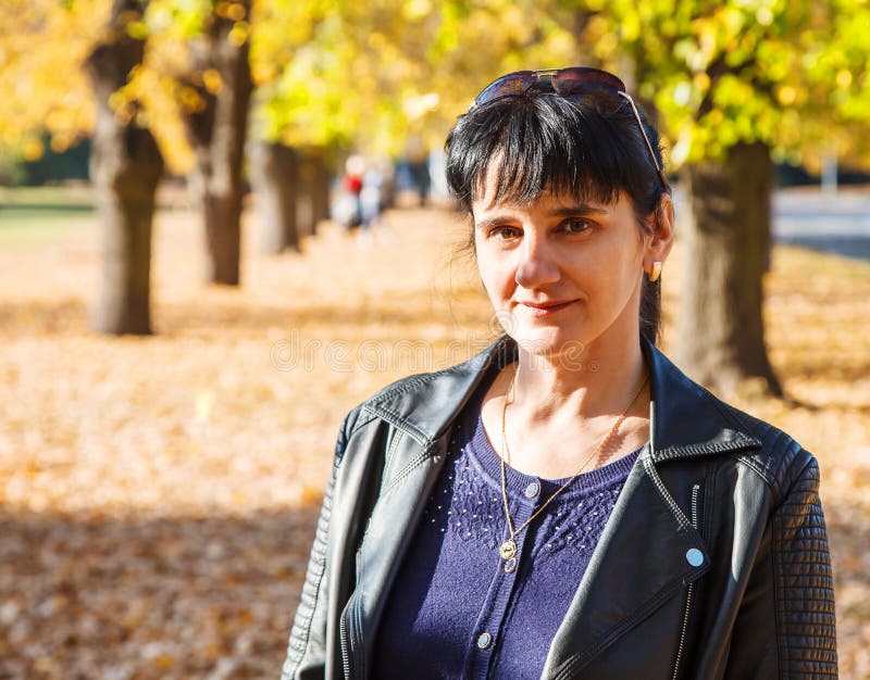 Femme de sourire de jeune brune sur une promenade en parc photographie stock libre de droits Femme de sourire de jeune brune sur une promenade en parc photographie stock libre de droits