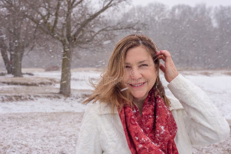 Femme de sourire marchant dans les bois tandis que les flocons de neige tombent photo libre de droits Femme de sourire marchant dans les bois tandis que les flocons de neige tombent photo libre de droits