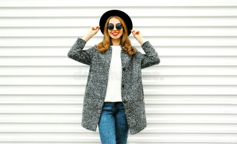Femme de sourire de mode dans le manteau gris, pose ronde noire de chapeau photos stock Femme de sourire de mode dans le manteau gris, pose ronde noire de chapeau photos stock