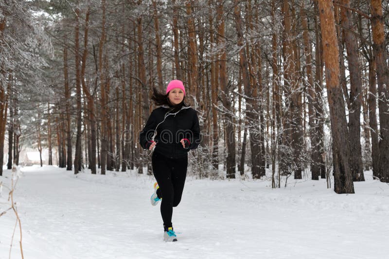 Une Femme Fait Du Jogging Dans Une Forêt D'hiver Dans Des Vêtements De  Sport Et Des écouteurs Chauds