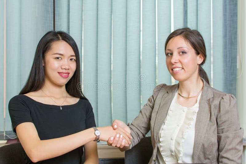 Femme des affaires deux se serrant la main par l'ordinateur image libre de droits Femme des affaires deux se serrant la main par l'ordinateur image libre de droits