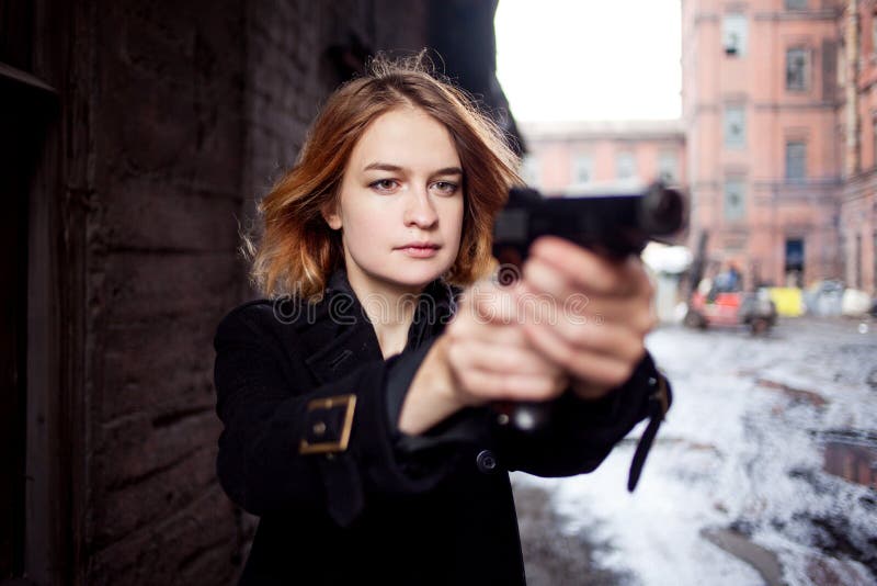 Femme dirigeant une arme à feu Tir de fille de Mafia à quelqu'un sur la rue image stock Femme dirigeant une arme à feu Tir de fille de Mafia à quelqu'un sur la rue image stock