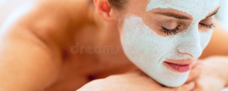 Femme décontractée avec le masque de revitalisation sur le visage s'étendant sur le MAS photographie stock Femme décontractée avec le masque de revitalisation sur le visage s'étendant sur le MAS photographie stock