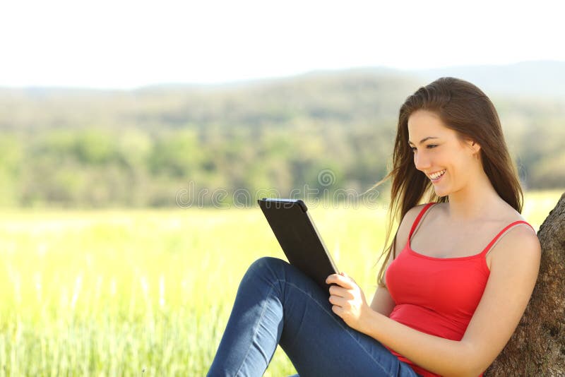 Femme décontractée lisant un ebook dans le pays image stock Femme décontractée lisant un ebook dans le pays image stock