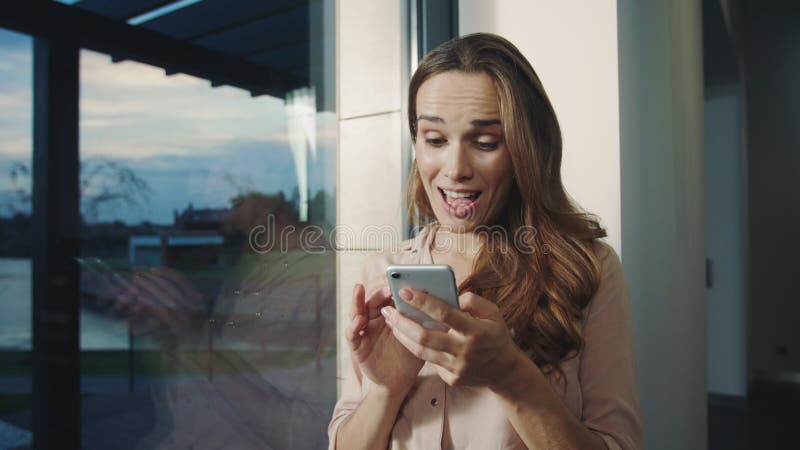 Femme décontractée recevant le message drôle sur le mobile Femme heureuse causant sur le téléphone portable