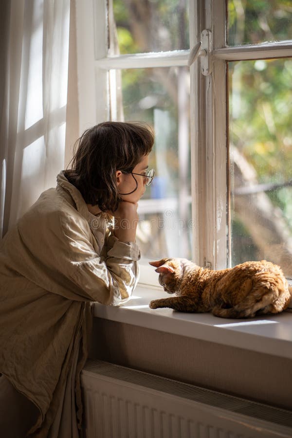 Femme déprimée penser à des ennuis tristement regarder fenêtre curieuse chat essayer soutien propriétaire. photographie stock