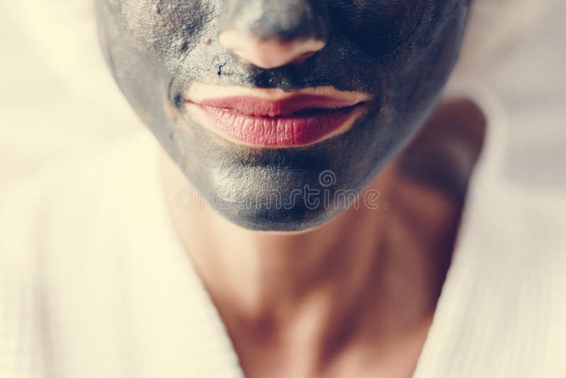 Femme détendant avec un masque de massage facial de charbon de bois photographie stock libre de droits Femme détendant avec un masque de massage facial de charbon de bois photographie stock libre de droits