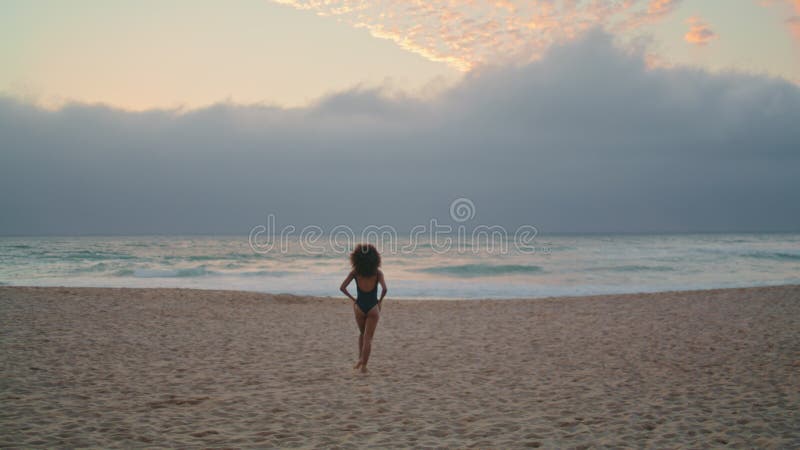 Femme détendue profiter de la promenade en bord de mer sur le sable près des vagues de l'océan arrière vue. banque de vidéos